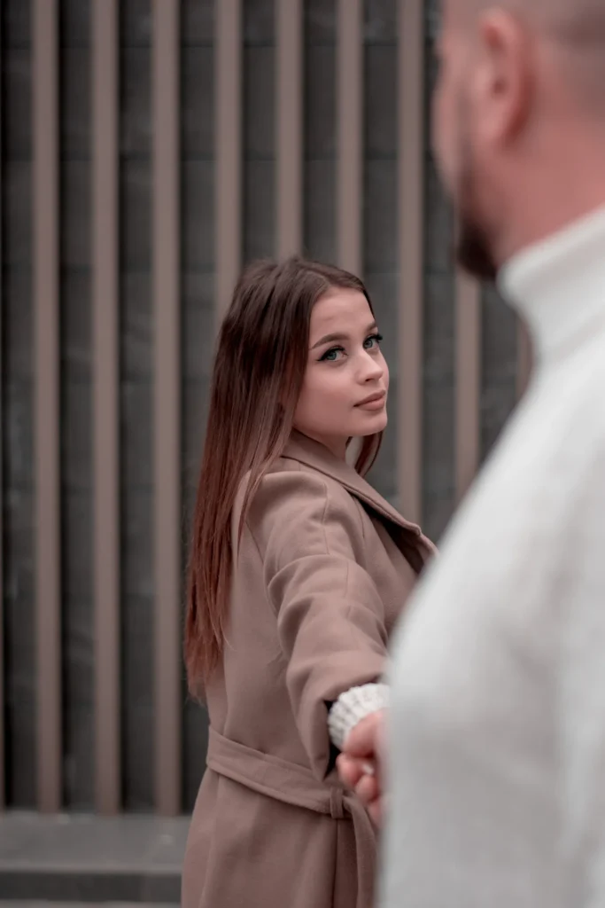Прогулочная love story в городе: девушка в пальто ведет парня за собой